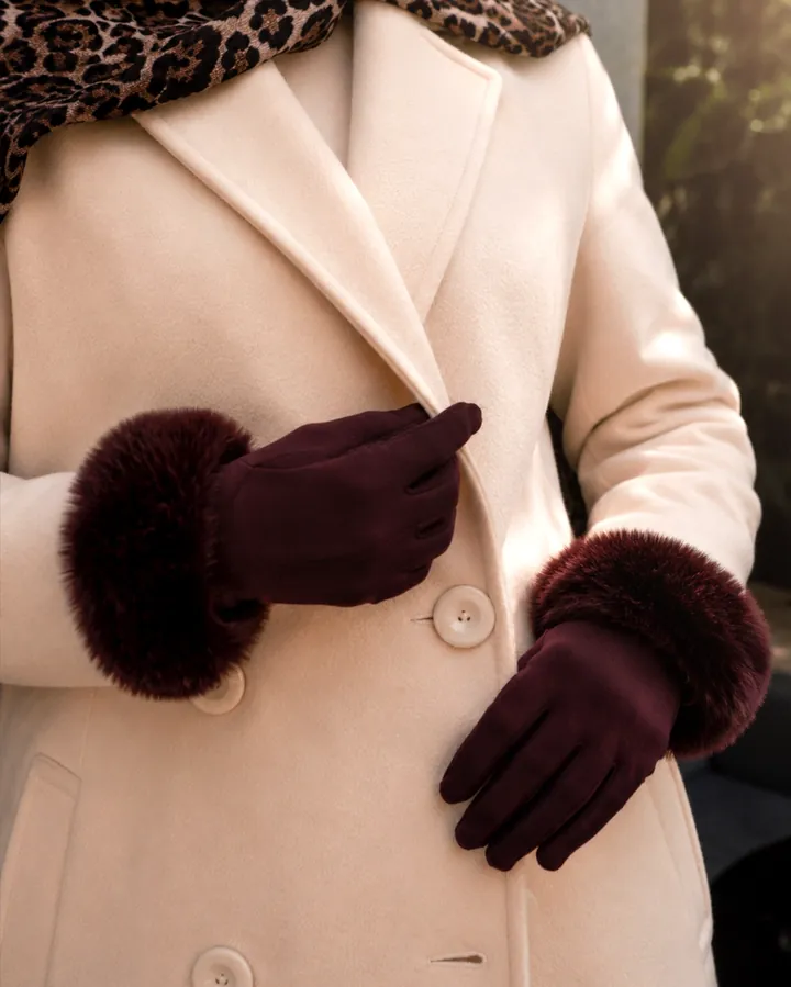 Close-up of burgundy fur-trimmed gloves against the buttons of a cream coat.