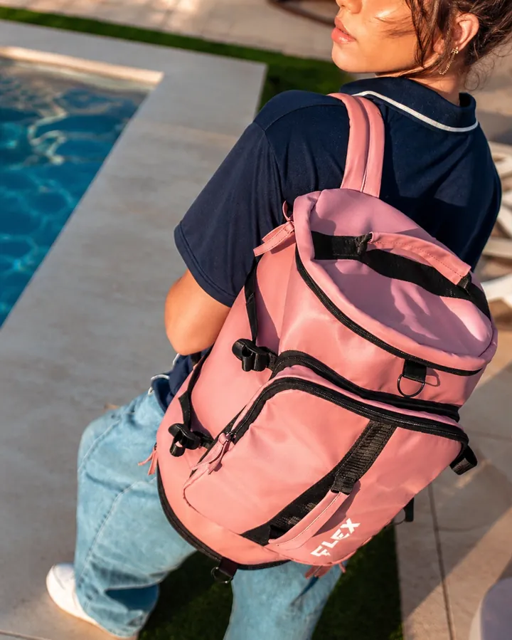 Side view of a pink backpack worn over a navy shirt beside the pool.